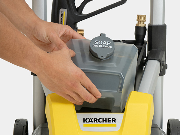 A person removing the detergent tank from the pressure washer