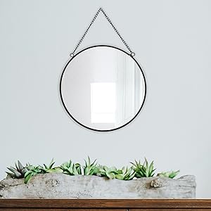 black metal rimmed wall mirror with chain with green deco below