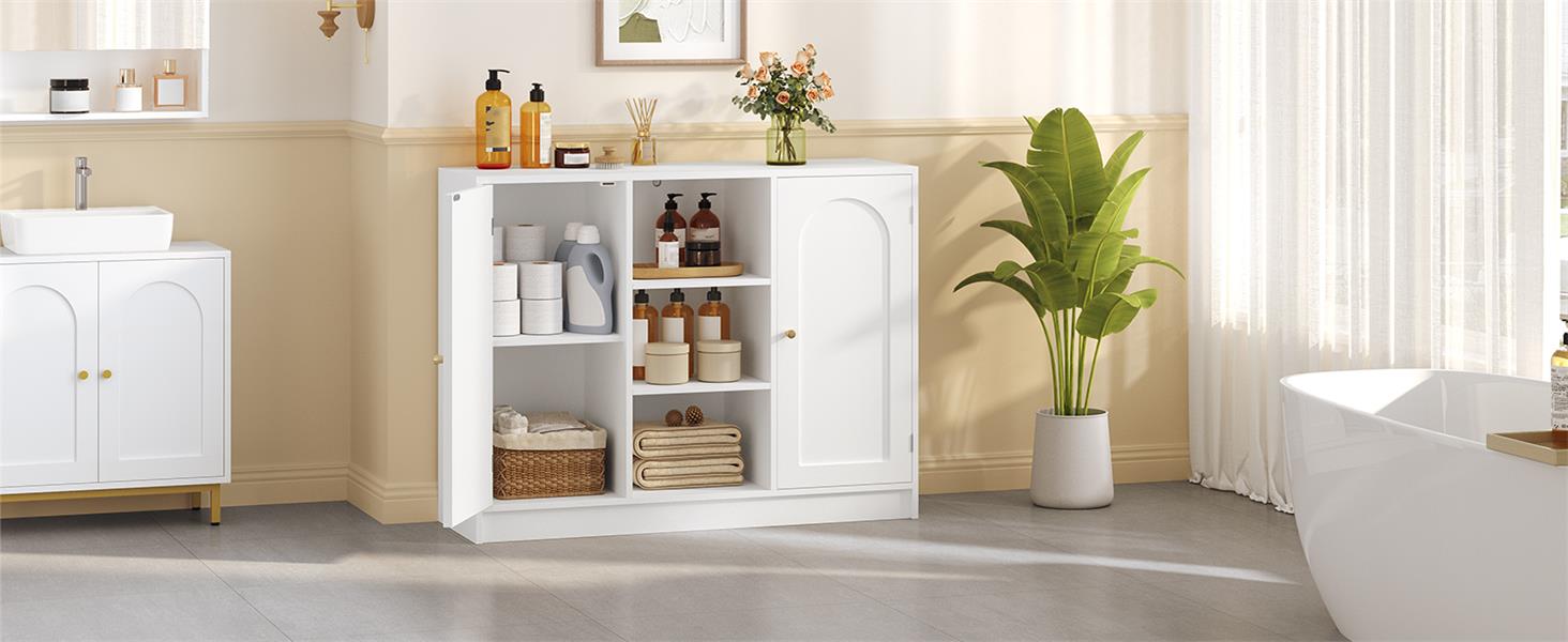 Weißer Badezimmerschrank aus Holz mit offenen Türen, die Regale zum Vorschein bringen. Enthält Toilettenartikel und Handtücher. Es befindet sich in einem hellen Badezimmer mit beigen Wänden und einer Topfpflanze in der Nähe