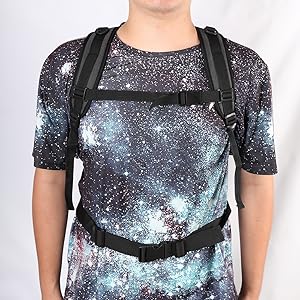 Nahaufnahme einer Person, die ein Hemd mit Galaxie-Print und verstellbaren schwarzen Trägern trägt, wahrscheinlich eine Babytrage oder eine Schürze.