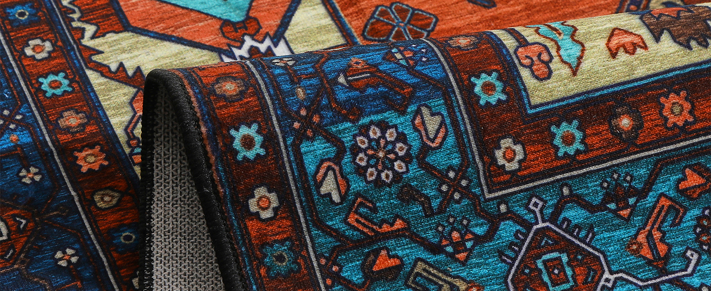 Detailansicht eines kunstvollen Teppichs mit geometrischen und floralen Mustern in Blau-, Rot- und Orangetönen mit komplizierten Randmustern