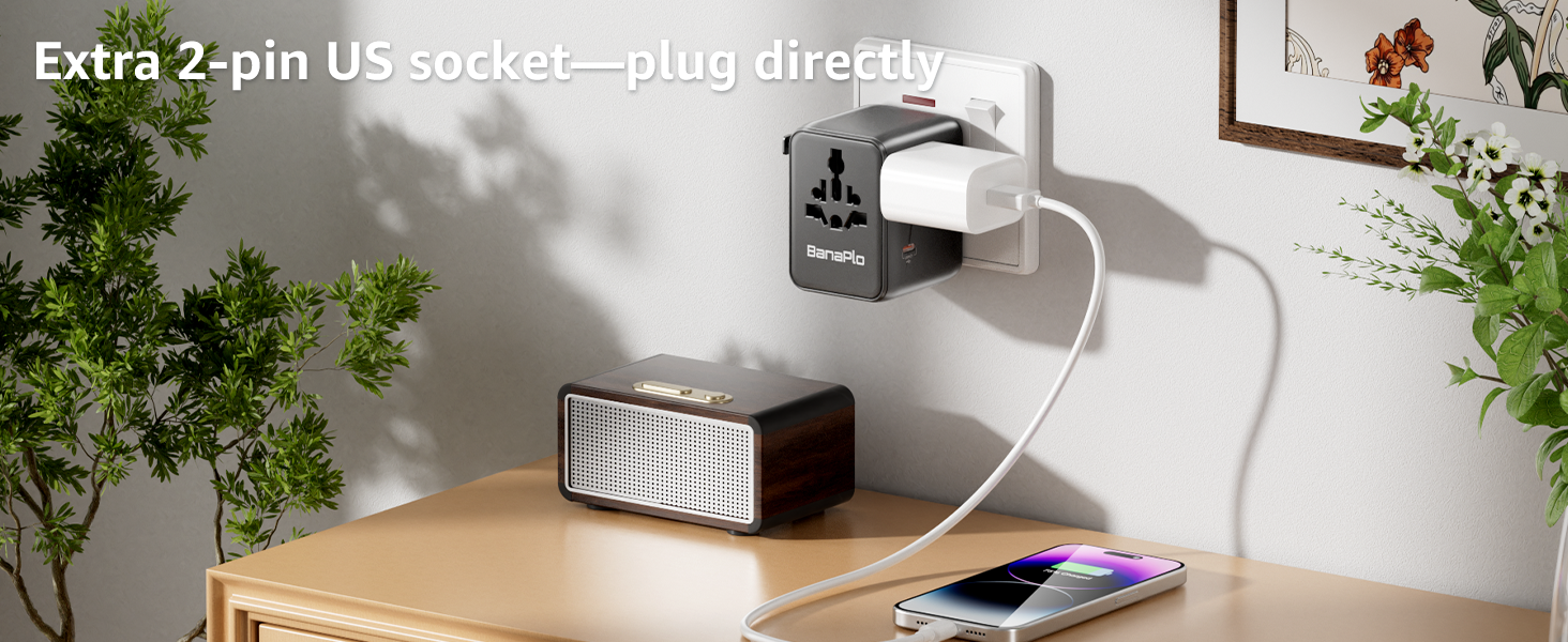 Wall-mounted power outlet extender or adapter shown in use with device plugged in, positioned on desk near indoor plants.