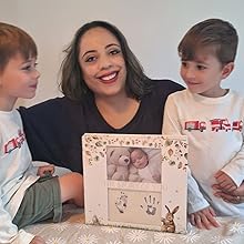 A mother sits with her children with their baby book as they cherish family memories together