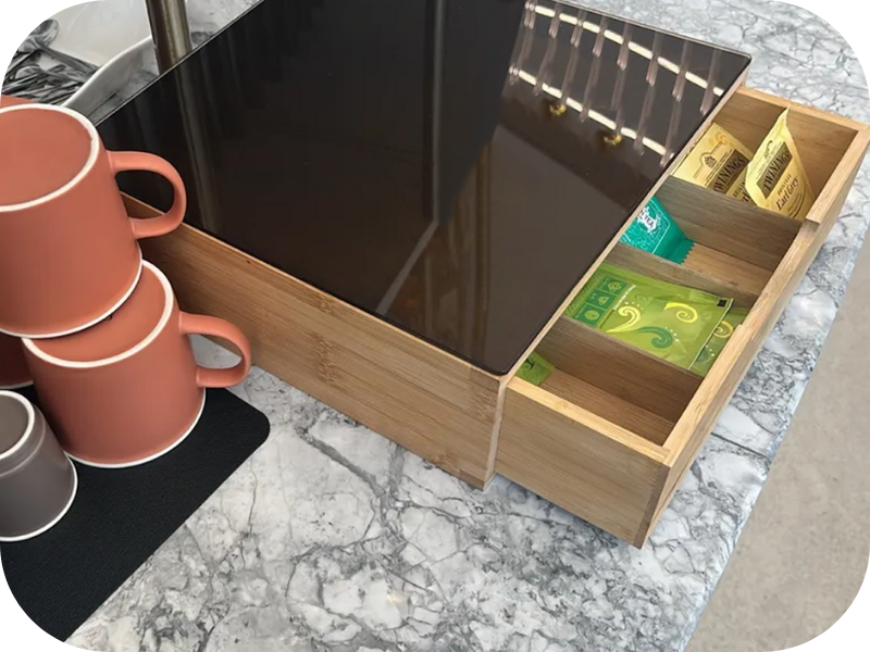 Postazione da caffè in legno con cassetto incorporato, che espone tazze in terracotta su un