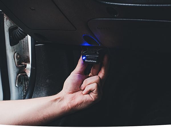 Man plugging BlueDriver's scan tool in the OBD2 port in vehicle to scan his car.