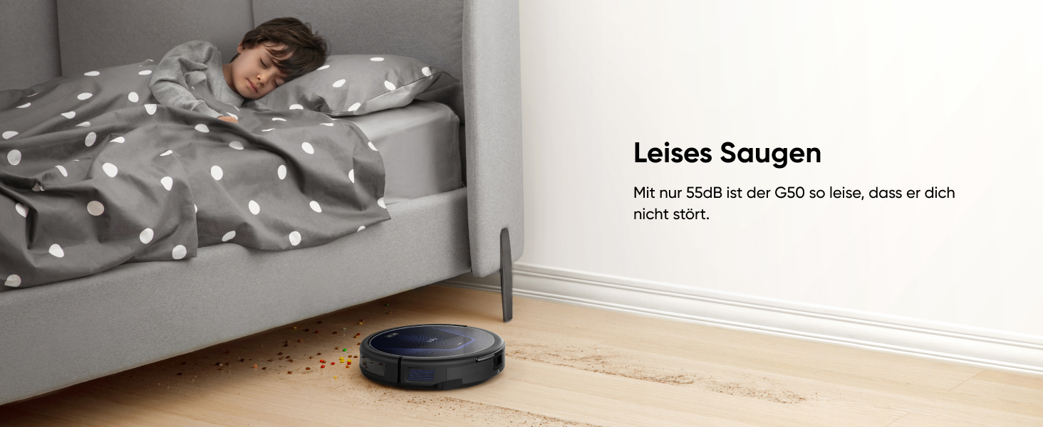 Scheibenförmiger Roboterstaubsauger auf Holzboden neben dem Bett mit gepunkteter Bettwäsche. Text 'Leises Saugen' oben sichtbar