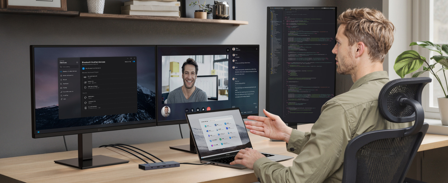 Man using ultrawide curved monitor displaying video call and code. Laptop and tablet on desk show additional screens. Ergonomic chair and floating shelves visible in home office setting.