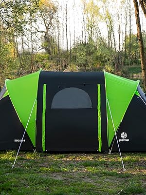 en colores negro y verde neón instalada junto a un lago, con alas laterales extendidas y una entrada central con soporte para guy-line