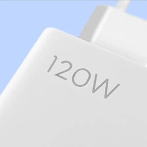 Primer plano de un dispositivo electrónico o adaptador blanco con la palabra «120 W» impresa en su superficie, sobre un fondo azul claro