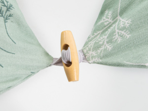 Nahaufnahme einer hölzernen Wäscheklammer oder Klammer mit mintgrünem Stoff- oder Papiermaterial