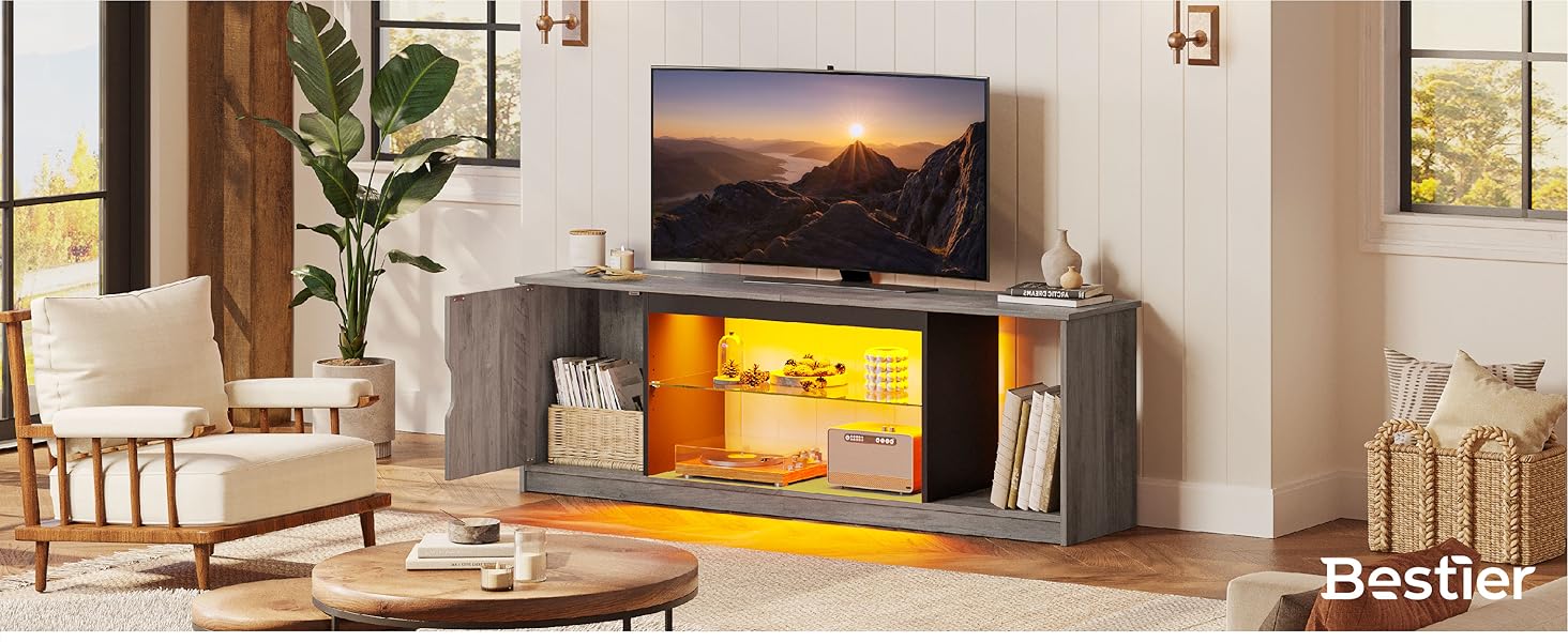 Moderner TV-Ständer mit beleuchteten gelben Regalen. Graue Oberfläche in Holzoptik, offene Staufächer. Zeigt Fernseher und Dekorationsgegenstände in einer gemütlichen Wohnzimmeratmosphäre