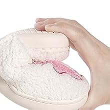 Heart-shaped white plush or cushion with pink decorative element being held in hands against white background.