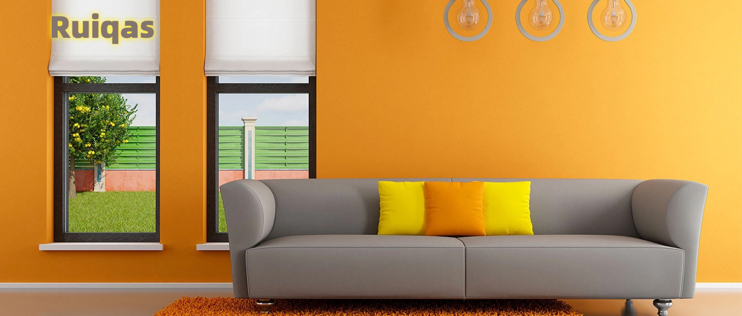 Interior de sala de estar con sofá gris, cojines amarillos y naranjas, alfombra naranja y paredes amarillas. Dos ventanas muestran una vista verde al exterior. Logotipo de Ruigas visible arriba.