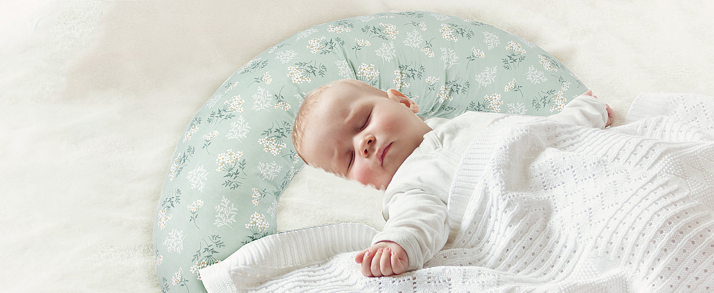 Schlafendes Kind auf mintgrün gemusterter Oberfläche, das weiße Strickkleidung trägt