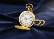 Gold pocket watch with chain on blue fabric background, elegant gift for men and special occasions