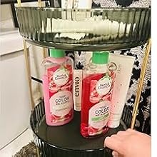 Green metal display rack holding pink bottles of Fabuloso cleaner. A hand is reaching for one of the bottles.