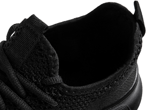Close-up of a black athletic shoe's upper part, showing textured fabric and lace eyelets.