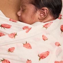 Baby sleeping in Tula's Tencel baby wrap in a strawberry-patterned print
