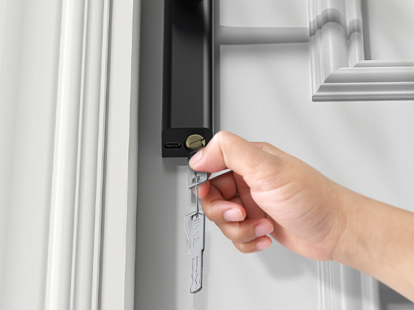 Close-up of a hand using a small metal tool to adjust or repair a white door hinge or latch mechanism.