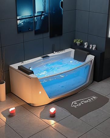 Moderne Badewanne mit transparenter Seitenwand, gefüllt mit blau beleuchtetem Wasser. Verfügt über integrierte Bedienelemente und Düsen. Es befindet sich in einem dunkel gefliesten Badezimmer mit stimmungsvoller Beleuchtung und Kerzen
