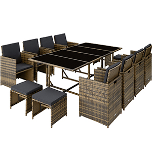 Grand ensemble de salle à manger d'extérieur avec chaises en osier et table en verre. Coussins foncés sur les sièges. L'ensemble semble pouvoir accueillir plusieurs personnes.