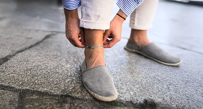 Adjustable surfer anklet in light blue and black worn by man on street in rolled-up pants.