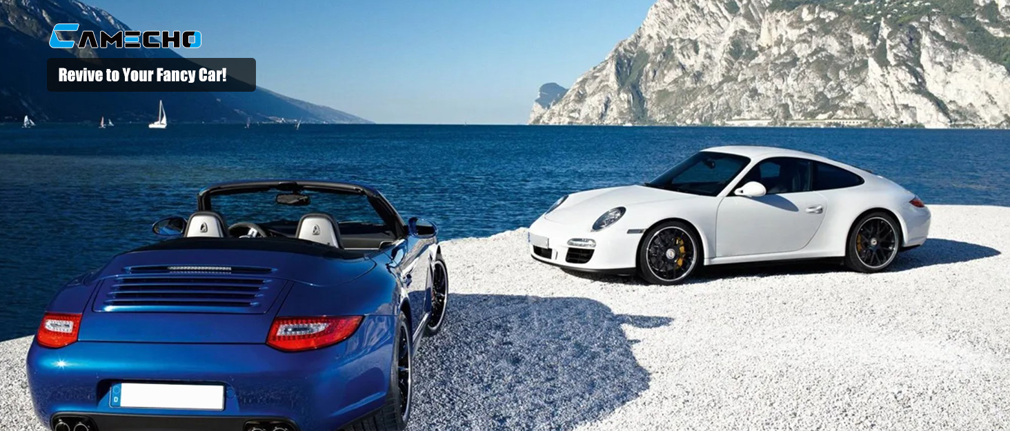Two luxury sports cars, one blue and one white, parked in a snowy mountain landscape setting.