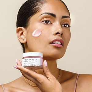 model holds alpyn beauty bounce cream with product on her face
