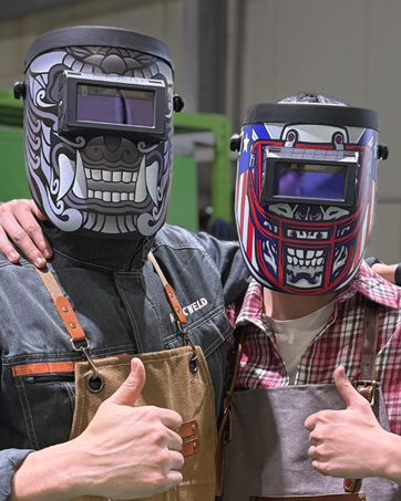 Two welders wearing Iconic Weld helmets giving thumbs up.