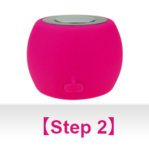 Small, spherical bright pink electronic device with a circular interface on top. Smooth surface texture with a power button symbol visible.