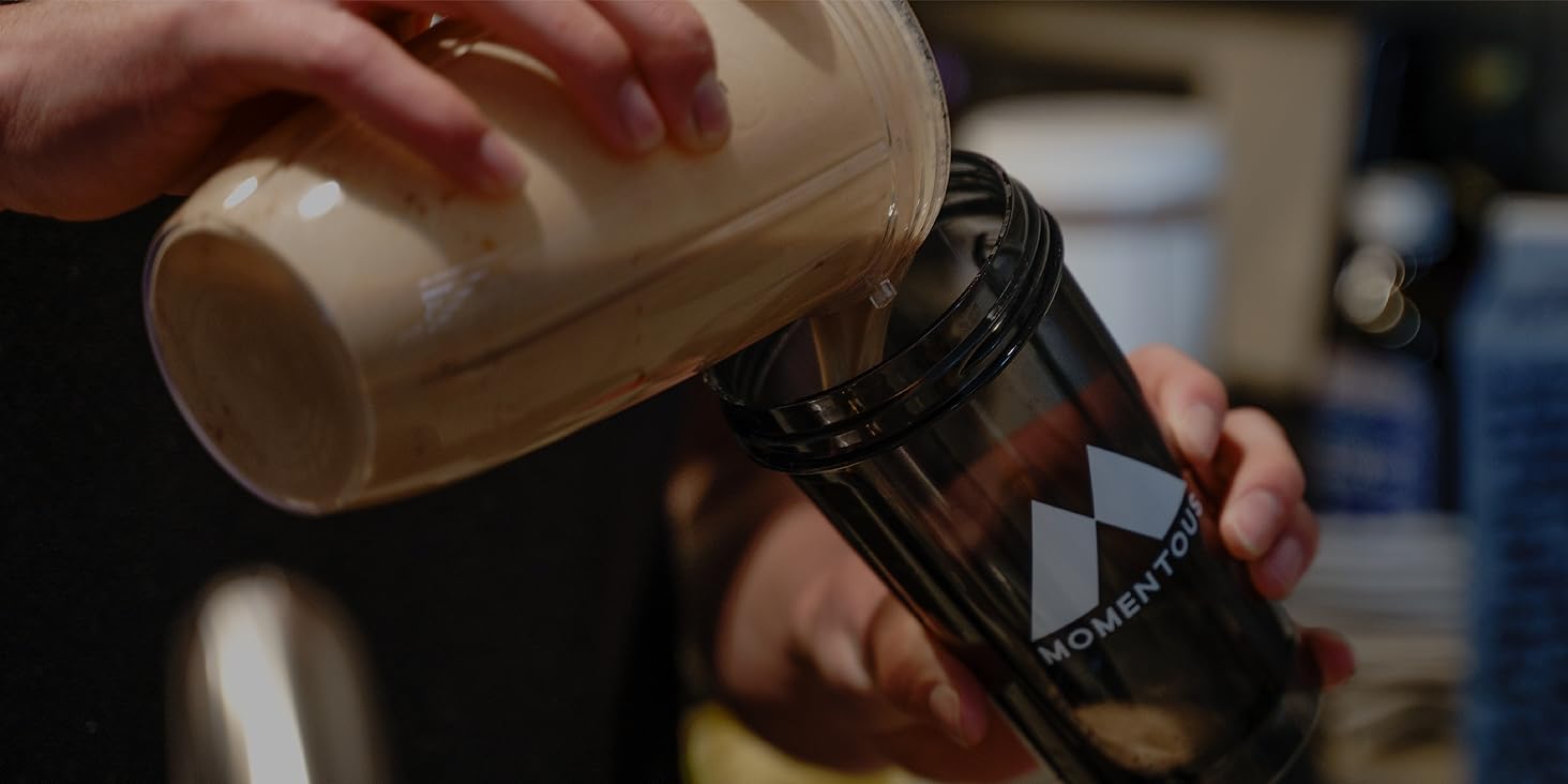 person pouring chocolate protein shake into momentous water bottle