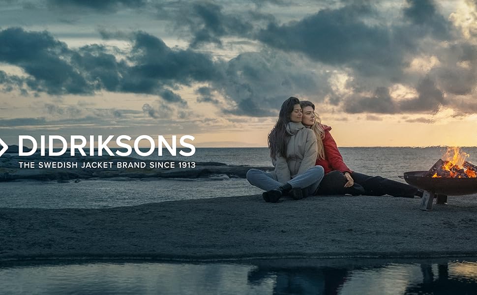 Zwei Frauen sitzen an einem Feuer an der Küste in wasserdichten Didriksons Jacken