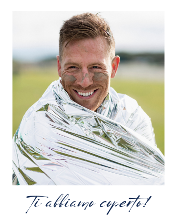 Un uomo sorridente coperto da una coperta di emergenza