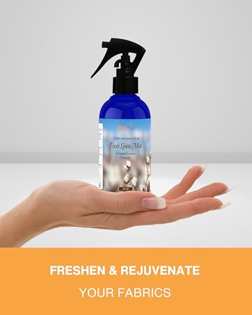 A woman's hand holding up a bottle of Fresh Linen scented linen mist. LinenMate LLC.