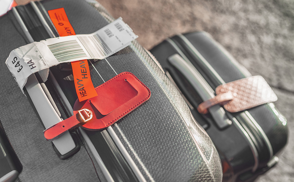 Close-up of luggage handles with red security tag attached, showing multiple gray suitcases with metallic handles in background.