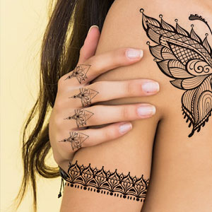 Ingewikkelde tatoeages in henna-stijl op hand en schouder. Fijne bloemen- en geometrische patronen sieren de vingers en creëren een armbandeffect