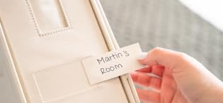 Woman slides label into plastic sleeve on the front of a LinenMate organizer. LinenMate LLC.