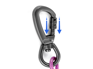 Metal carabiner with dual-action locking mechanism. Blue arrows indicate sliding motion. Small pink object attached to demonstrate usage.