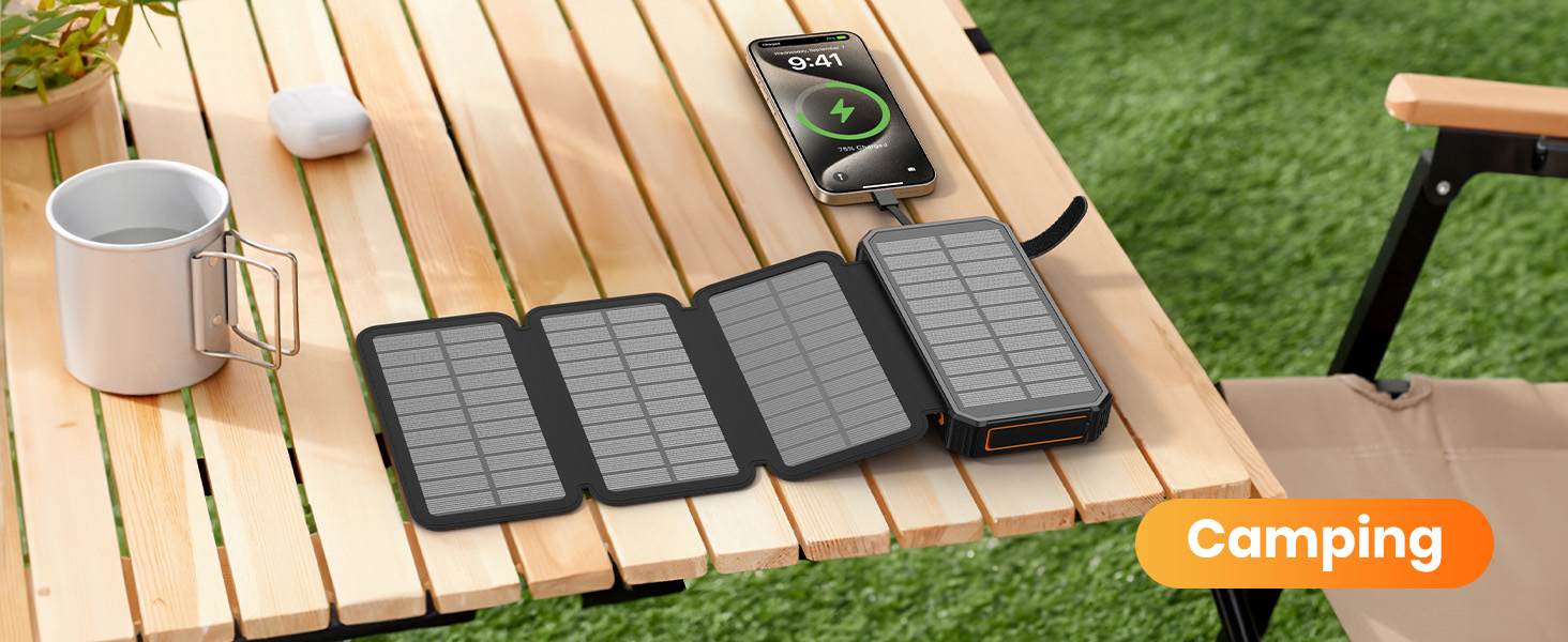 El texto dice «Campamento». Varios bancos de energía solar se muestran sobre una mesa exterior de madera con una taza de café, sobre un fondo de césped verde.