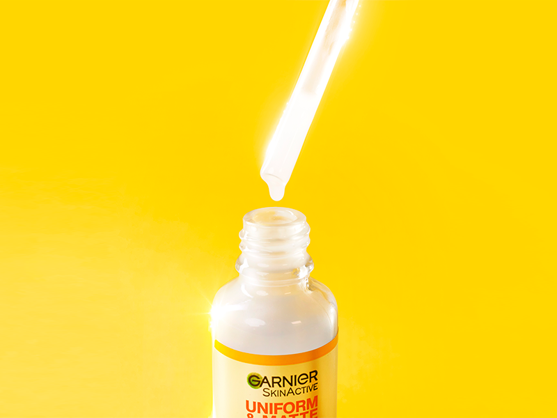 Sérum Antimanchas com conta gotas em destaque sobre fundo laranja