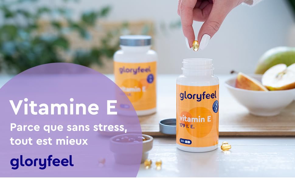 Supplément de vitamine E en bouteille orange. Placer la capsule à la main dans un récipient blanc. Fruit et bouteille de la marque « Gloryfeel » visibles