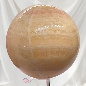 Der Text lautet „Bild 2“. Nahaufnahme, die etwas zeigt, was wie ein ovales Objekt aus Holz oder Naturfarbe aussieht, mit Nähdetails auf einer weißen Oberfläche.