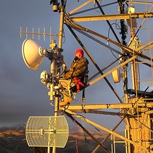 Man on top of tower with Cambium Networks radio equipment