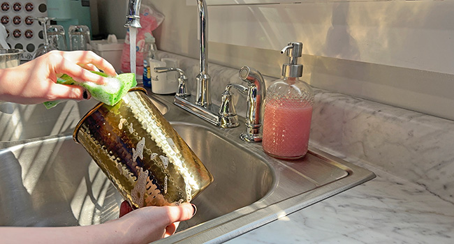 Image of person washing the utensil holder in a kitchen sink