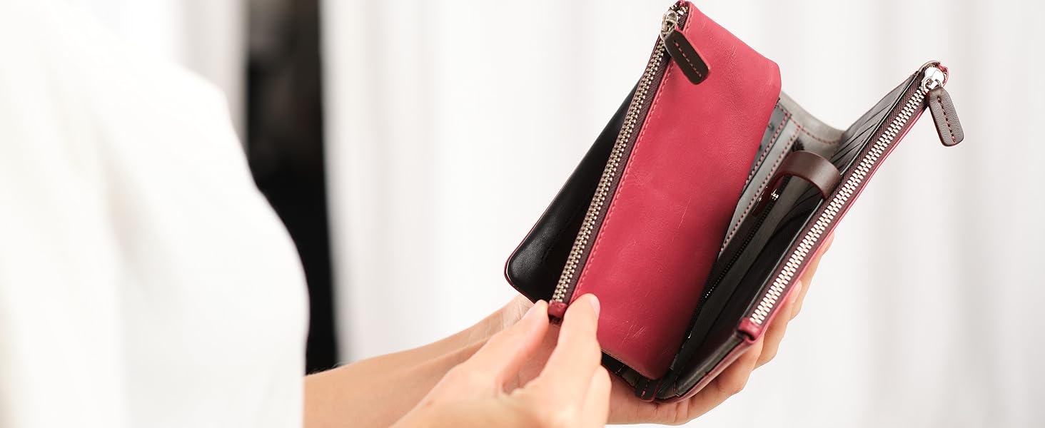 a woman holding a red leather wallet with a black and white purse inside.