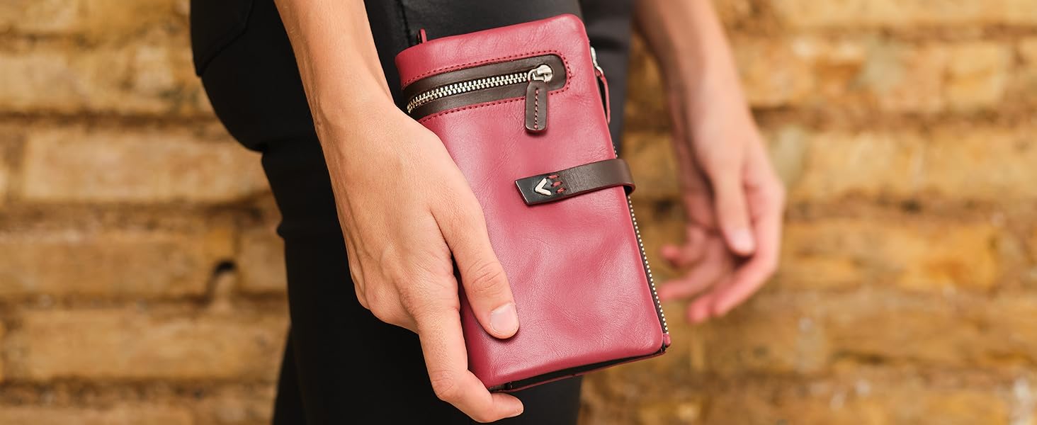 a woman holding a red leather wallet with a black and white purse inside.