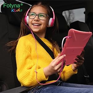 Felice bambina viaggia in macchina con tablet per bambini "Fotyna" ascoltando la musica.