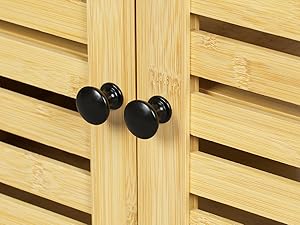 Close-up of wooden cabinet doors with black round knobs, showcasing the grain and slat design of the light-colored wood construction.