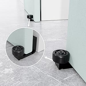 Black circular door stopper with wedge-shaped base, shown in use and close-up. Designed to hold doors open on hard floors.