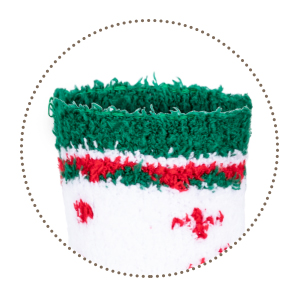 Close-up of a green knitted or crocheted item with a red cross pattern, possibly a Christmas-themed decoration or ornament.